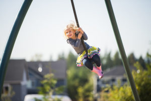 A young girl smiling on her swing that is in mid-air