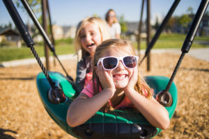 Two sisters smiling on swing
